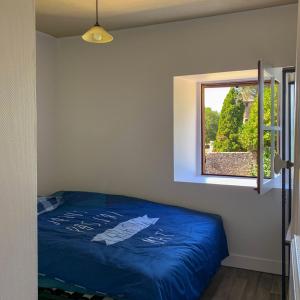 une chambre avec un lit bleu et une fenêtre dans l'établissement House with a private hot tub and medieval garden, à Saint-Pierre-de-Frugie