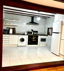 Eine Küche mit weißen Geräten und weißem Fliesenboden in der Unterkunft Arbide, caserio tradicional vasco en Carranza in Karrantza