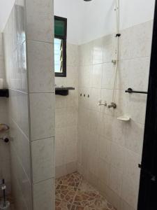 a shower with a glass door in a bathroom at Raine house in Ukunda