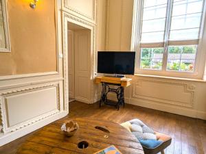 a living room with a table and a television at Gîte confortable pour 4 personnes avec jardin et terrasse près de Nancy - FR-1-584-102 in Villey-le-Sec