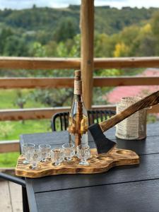 a bottle of wine and glasses on a wooden cutting board at Cabana Arini 1954 in Vişeu de Jos