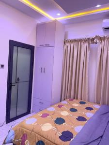 a bedroom with a bed and a cabinet and curtains at Modern 3-Story Condo with Private Rooftop Lounge in Amasaman