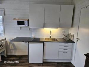 a kitchen with white cabinets and a sink at Färjas Brygga in Söråker +2 photos