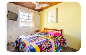 a bedroom with a colorful bed and a television at Casa Bromélia, a 15 minutos a pé do centro histórico! in Paraty