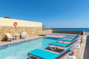 ein Pool mit Stühlen und das Meer im Hintergrund in der Unterkunft The Cottage South Escape with beach front pool in Plimmiri