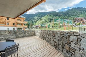 a patio with a stone wall and a table and chairs at Tome, superbe appartement avec terrasse vue montagne in Champagny-en-Vanoise