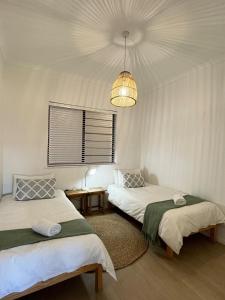 two beds in a room with a chandelier at Atlantic Apartment - spacious kite accommodation in Langebaan +12 photos