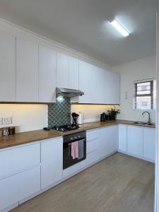 a kitchen with white cabinets and a stove top oven at Atlantic Apartment - spacious kite accommodation in Langebaan