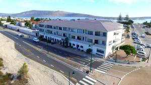 a large white building with cars parked in a parking lot at Atlantic Apartment - spacious kite accommodation in Langebaan