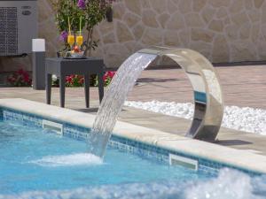 a water fountain in a pool in a resort at Grebastica Poolside Villa in Grebaštica +32 photos