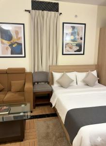 a hotel room with two beds and a couch at Govinda Hall in Kānpur