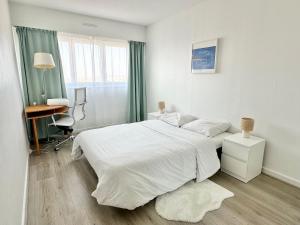 a white bedroom with a large bed and a desk at Le Gémeaux - Paris - La Défense vue d'exception in Courbevoie