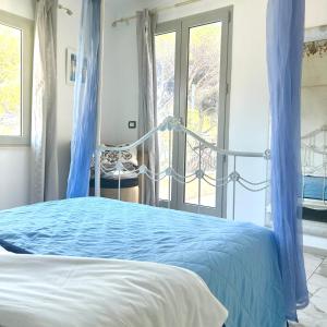 a bedroom with a bed with blue curtains and a window at Villa sur mer, chez Angelina in Grimaud