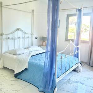 una camera da letto con letto a baldacchino con lenzuola blu e finestra di Villa sur mer, chez Angelina a Grimaud Altre 22 foto