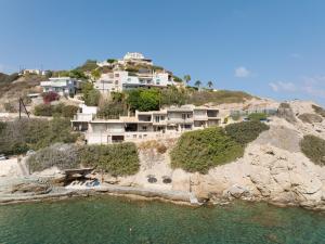 a house on top of a hill next to the water at Nere Suites in Lygaria
