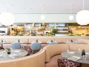 a restaurant with tables and chairs and a kitchen at Fairmont Pacific Rim in Vancouver