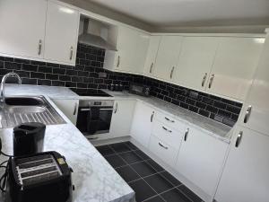 a kitchen with white cabinets and a sink and a counter at South Liverpool Cozy Home in Halewood
