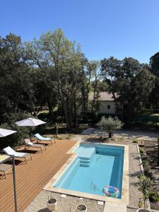 Una piscina con sillas y sombrillas en un patio. en Villa Mimosa, en Venasque