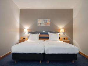a hotel room with two beds and two lamps at Swissôtel Amsterdam in Amsterdam