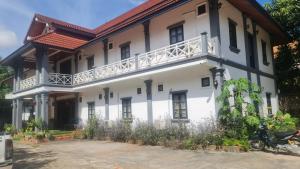 a white building with a balcony on top of it at The ziong's inn guesthouse in Luang Prabang +17 photos
