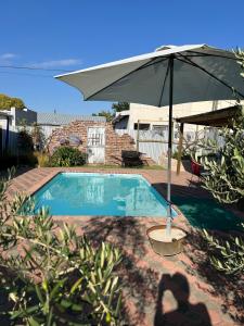 an umbrella sitting next to a swimming pool at Tuinhuis in Oudtshoorn