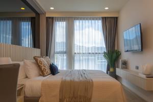 a bedroom with a bed and a large window at Bangtao Golf View Apartments in Laguna Phuket