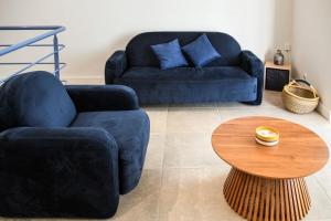 Una sala de estar con dos sofás azules y una mesa. en Villa Faraman au bord de l'eau, en Le Grau-du-Roi