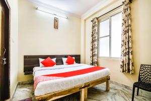 a bedroom with a bed with red pillows and a window at Hotel O Prayag in Jaipur +37 photos