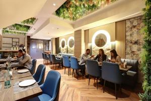 a group of people sitting at tables in a restaurant at HOTEL UPTOWN with Luxury Restaurant & Rooftop Near Connaught Place, New Delhi City Centre in New Delhi +41 photos
