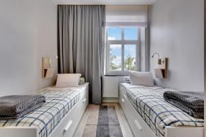 two beds in a room with a window at Lion Apartments - NEMO Family 2 Bedr Apartment with parking, terrace and 3 min from the beach in Sopot