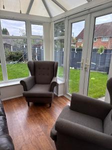 a living room with a couch and chairs and windows at Spacious Luxurious Serviced Accommodation 1 in Walsall