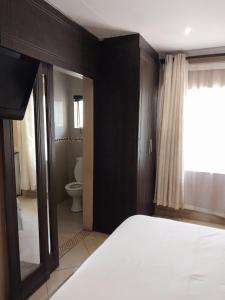 a bedroom with a bed and a bathroom with a toilet at Nomanini Guesthouse in Nelspruit