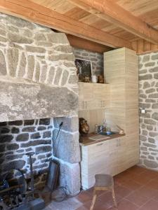 a kitchen with a stone fireplace with a sink at La maison des Florentins La Monédière in Chaumeil
