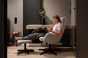 eine Frau, die auf einem Stuhl sitzt und ein Buch liest in der Unterkunft Kraków Wawrzyńca Suites by Downtown Apartments in Krakau