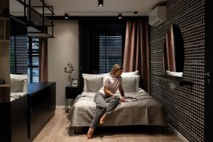 eine Frau, die auf einem Bett in einem Zimmer sitzt in der Unterkunft Kraków Wawrzyńca Suites by Downtown Apartments in Krakau