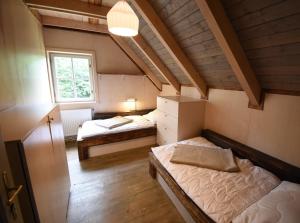 an attic room with two beds and a window at Roubenka Studánka in Studený