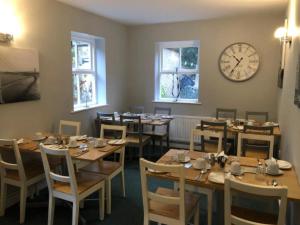 a dining room with wooden tables and a clock on the wall at The Georgian Guesthouse in Alnwick