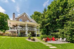 a large white house with a yard with green grass at Escale Vélo & Spa en Estrie in Shefford