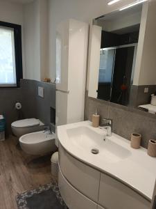 Un baño con lavabo, inodoro y espejo. en Casa Vacanze Da Anna, en Grosio