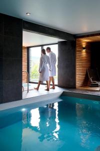 two people standing next to a swimming pool at Hôtel Panorama - Vue exceptionnelle sur la Semois in Bouillon