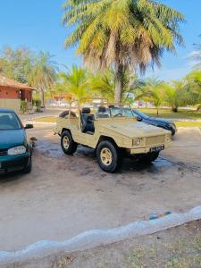 une jeep beige garée sur un parking avec un palmier dans l'établissement Wunderland River Lodge, à Kubuni