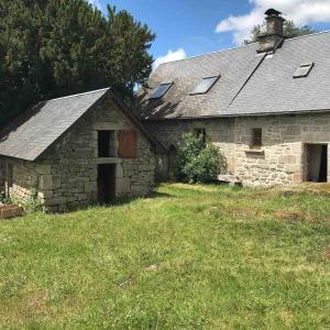 an old stone house with a grass field in front of it at La maison de Baptiste La Monédière in Chaumeil