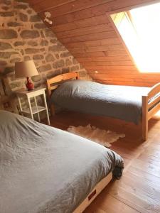 two beds in a room with a stone wall at La maison de Baptiste La Monédière in Chaumeil