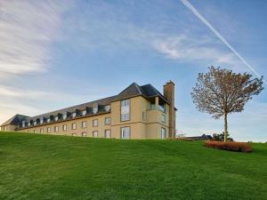 ein großes Gebäude auf einem grasbewachsenen Hügel mit einem Baum in der Unterkunft Fairmont St Andrews, Scotland in St Andrews