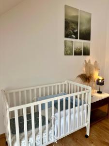 a white crib in a room with paintings on the wall at Apartma La Vie in Kostanjevica na Krki +3 photos