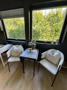 sala de estar con 2 sillas, mesa y 2 ventanas en Lillestrøm , the studio flat, en Kjeller