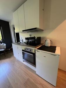 Una cocina con gabinetes blancos y un horno de estufa. en Lillestrøm , the studio flat, en Kjeller
