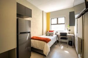 a small bedroom with a bed and a refrigerator at Peak Studios Cape Town in Cape Town