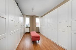a dressing room with white cabinets and a red bench at Family Apartment with 3 Bedrooms & Air Conditioning in the Centre of Wrocław by Noclegi Renters in Wrocław