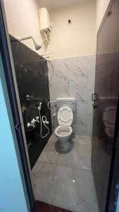 a bathroom with a white toilet in a stall at Gugan home stay in Tiruchchendūr
